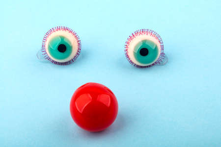 Decorative fruit candy eyes with red nose over light blue background. Conceptual photo using for funny celebration themes.の写真素材