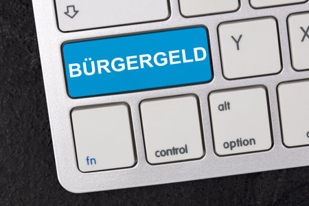 Keyboard with german word BÃ¼rgergeld ( engl. citizen money) isolated on dark background. New financial help system in Germany. Social support concept.の写真素材