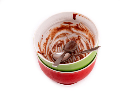 Empty chocolate pudding bowl with two tea spoons over white background.の写真素材