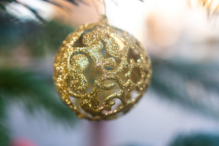 Decorative golden Christmas Ball on a fir tree outdoor in detailの写真素材