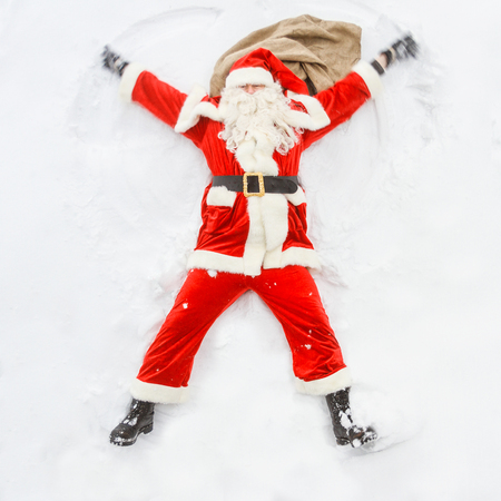 Happy Santa Claus makes a snow angel in the snowfall.の写真素材