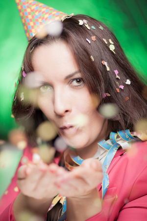Attractive woman blowing confetti and celebrating something.の写真素材