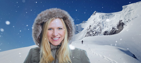 Snowy winter scenery with high moutains and a smiling attractive woman in the foreground.の写真素材