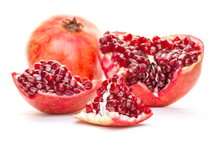 A whole pomegranate disassembled into parts isolated on white background. Healthy red food, diet and organic fair trade concept.の写真素材