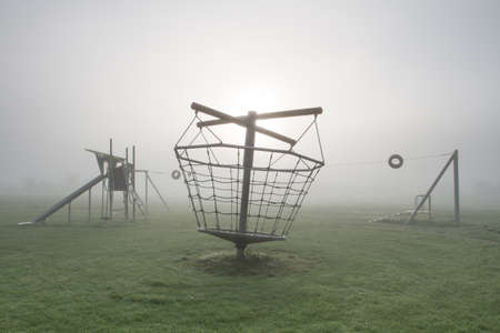 A deserted children's playground on a cold and foggy morning.