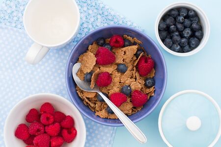 A healthy breakfast of cereal, raspberries and blueberries. A view looking down from above onto the table.の写真素材