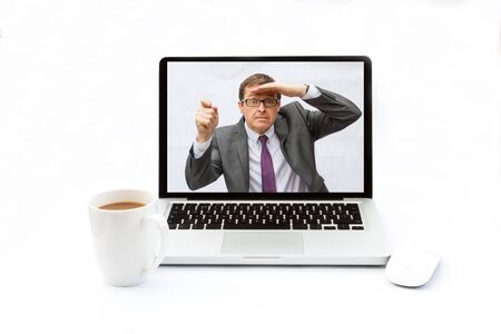 A businessman trapped inside a laptop looking for help from IT. White desk with isolated white background.の写真素材
