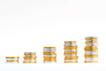 Gold and silver coins on an isolated white background and in the shape of an upward growth graph.の写真素材