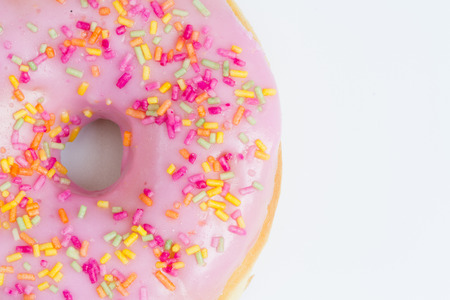 A large doughnut with pink icing and sprinkles on an isolated white background.の写真素材