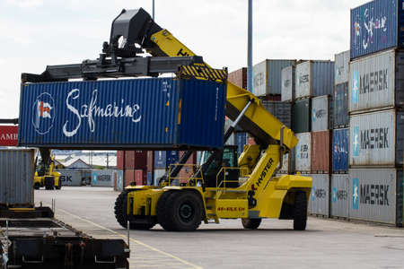 DONCASTER, YORKSHIRE, UK - JULY 30, 2016. A heavy lifting machine loading and stacking a freight train with cargo and shipping containers in Doncaster Rail Port for onward movement to docks in the UK ready for export.のeditorial素材