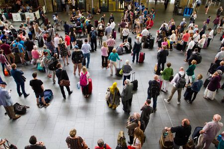 KING'S CROSS, LONDON, UK - JULY 21, 2016. Crowds of passengers, commuters and travellers waiting patiently in the concourse of King's Cross railway station for information about their trains.のeditorial素材