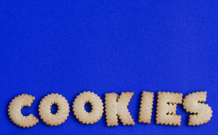 The word cookies created from alphabet shaped biscuits at the bottom of the frame with copy space above and a blue background.の写真素材