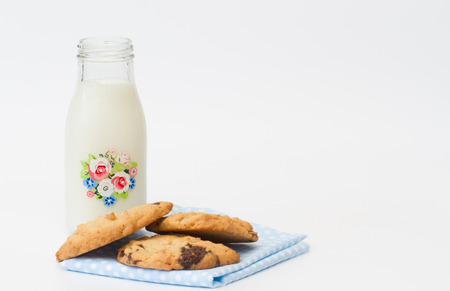 A stack of homemade peanut butter and chocolate cookies and a bottle of fresh milk on an isolated white background.の写真素材
