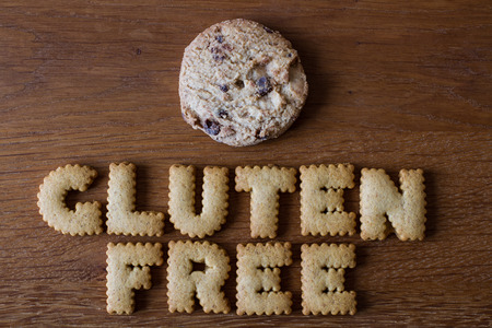 The phrase Gluten Free created from alphabet shaped cookies with a single chocolate chip biscuit and on a wooden background. Healthy eating advice.の写真素材