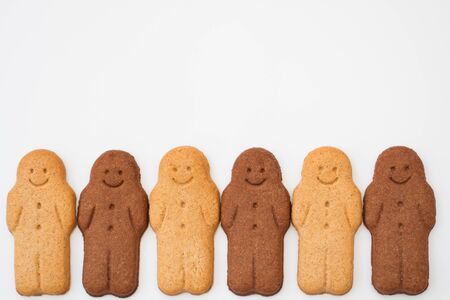 A row of black and white Gingerbread Men smiling and looking happy representing racial harmony, equality and diversity on an isolated white background.の写真素材