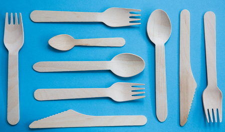 A variety of recyclable wooden cutlery including knife, fork and spoon on a blue backgroundの写真素材
