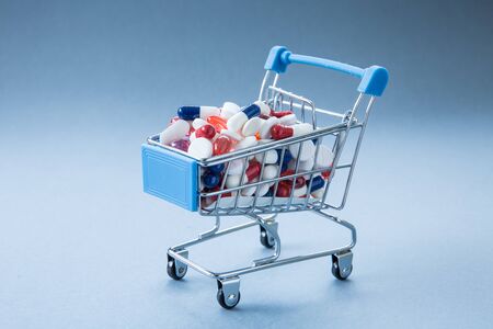 A concept image of a retail, shopping trolley or cart full of pills, tablets, antibiotics, paracetamol, painkillers and antidotes to viruses, bacteria and infectious diseases such as Coronavirus and Covid 19 making them resistant with copy spaceの写真素材