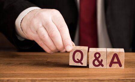 A Q & A or question and answer concept of the phrase spelled out in wooden blocks by a male business handの写真素材