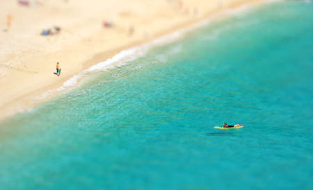 Aerial view of a surfer floating on a calm ocean in Cornwall with turquoise sea and white sandy beach with copy spaceの写真素材