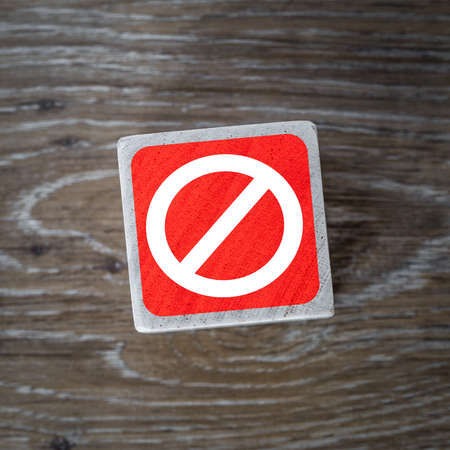 A red stop sign, symbol or icon on a wooden block and wood background with copy spaceの写真素材
