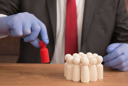 Coronavirus concept of a man in a suit removing an infected person from a group of people because of Coronavirus with copy spaceの写真素材