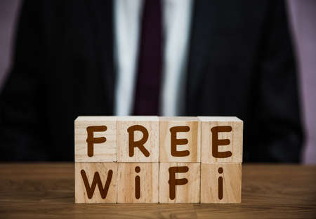 A sign saying Free Wifi for customers of hotels, retail and internet cafe in an internet, broadband connectivity background with copy spaceの写真素材