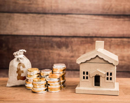 A housing property concept with a home and stacks of money representing family savings and cost of housing or rental with copy spaceの写真素材