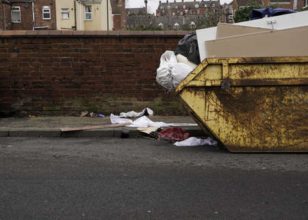 An overflowing skip with household waste littering pavements and roads with copy spaceの写真素材