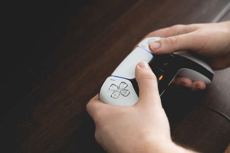 SELBY, UK, MARCH 11, 2021.  Close up of a pair of male hands using and playing with a Playstation PS5 controller handset with copy spaceのeditorial素材