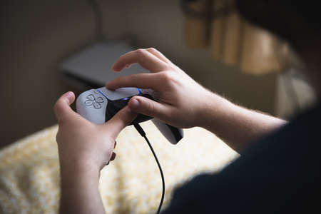 YORK, UK - MAY 9, 2021.  Close up of a teenage boy holding a PS5 gaming console controller and using the joypad with his fingersのeditorial素材