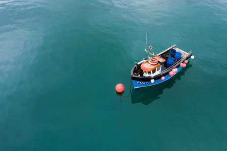 COVERACK, CORNWALL, UK - JUNE 24, 2021.   A traditional Cornish fishing boat floating on a beautiful calm ocean with copy spaceのeditorial素材