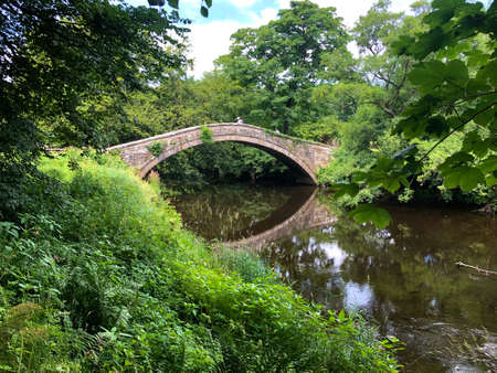 An old fashioned humpback stone arched bridge over a river in the English countrysideの写真素材
