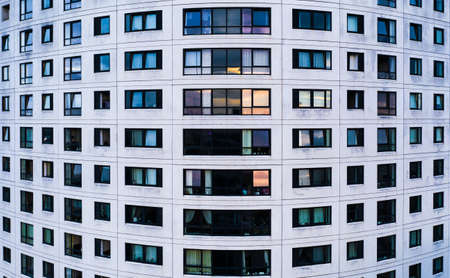 Full frame real estate background of rows of windows in a colourful apartment block with a curved...