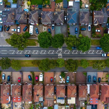 An aerial view of a tight knit suburban neighbourhood in the UK with a busy road running throughの写真素材