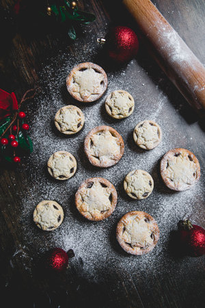 A home baking concept of traditional Christmas mince pies arranged in the shape of a Christmas Tree and covered in icing sugarの写真素材