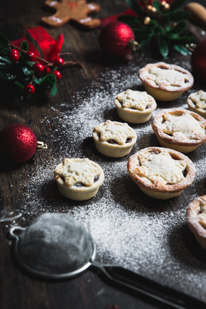 A home baking concept of traditional Christmas mince pies arranged in the shape of a Christmas Tree and covered in icing sugarの写真素材