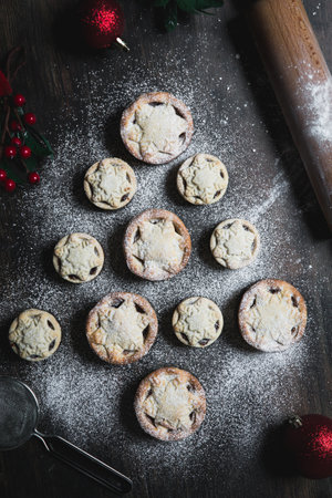 A home baking concept of traditional Christmas mince pies arranged in the shape of a Christmas Tree and covered in icing sugarの写真素材