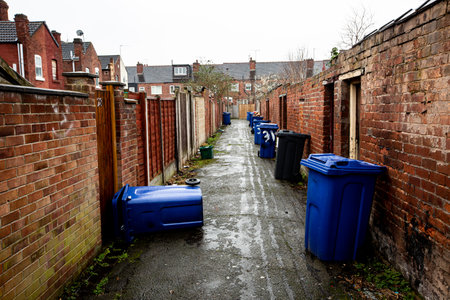 The backstreet of rows of terraced houses in a run down city in Northern England with wheelie bins left out for roadside collection with copy spaceの写真素材