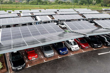 STOURTON, LEEDS, UK - MAY 16, 2022.  Aerial view above innovative solar panels located on a car parking lot rooftops making good use of small space in a cityのeditorial素材