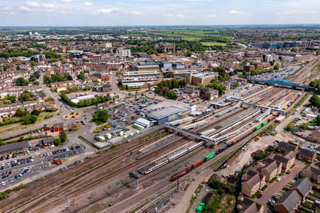 PETERBOROUGH, UK - MAY 17, 2022.  An aerial landscape view of passenger and freight trains waiting on the platforms of Peterborough train station on the East Coast Main Line railway with the city in the backgroundのeditorial素材
