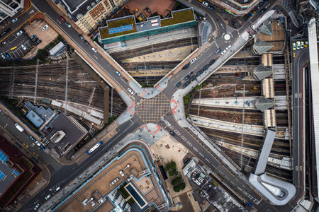 An aerial view directly above an urban metropolis with crossroad street junction over busy railway and subway train tracksの写真素材