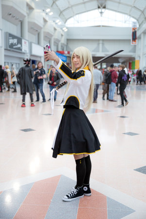 BIRMINGHAM NEC, UK - NOVEMBER 13, 2022.  A young Korean cosplayer girl dressed as a popular Korean or Japanese Yugioh Anime character and taking a selfie for social media at a comic conのeditorial素材