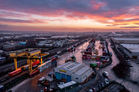LEEDS, UK - JANUARY 19, 2023.  An aerial view of Freightliner Intermodal container terminal in Leeds at sunset with heavy machinery loading container boxes onto rail and road transportのeditorial素材