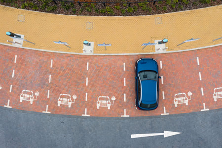 Aerial view directly above an electric vehicle charging station with parking spaces and road markings denoting charging baysの写真素材
