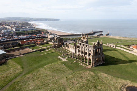 WHITBY ABBEY, UK - MARCH 12, 2023.  An aerial landscape view of the profile of the ruins of Whiby Abbey  on the North Yorkshire coast with ocean and beach in the backgroundのeditorial素材