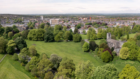 An aerial cityscape of Harrogate town with The Stray public park and local church