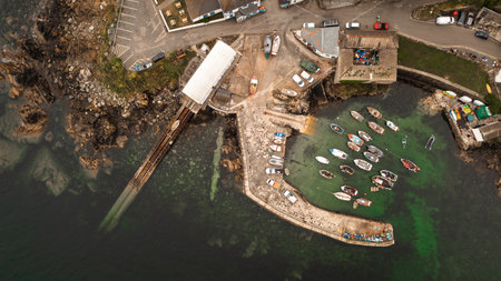Aerial landscape of the quaint Cornish fishing village of Coverack in Cornwall with old lifeboat station slipway and tidal harbour with traditional fishing boatsの写真素材
