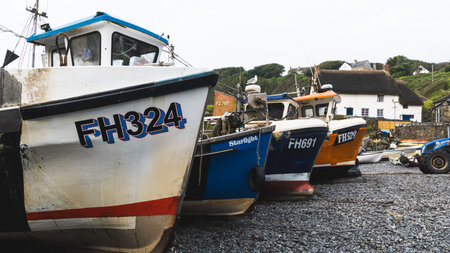 CADGWITH, CORNWALL, UK - JULY 1, 2023.  Traditional Cornish fishing boats out of the water and on the pebble beach at the popular tourist destination of Cadgwith in Cornwallのeditorial素材