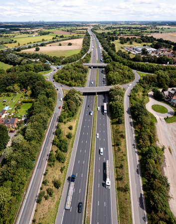 Aerial vertical panorama directly above a busy road intersection cutting through countryside on the M62 motorway heading East towards Hull in the UKの写真素材