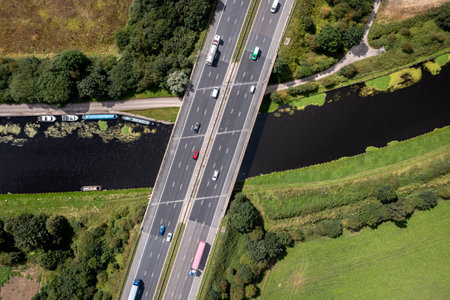 Aerial view directly above a busy UK motorway passing over a river or canal bridge in the countrysideの写真素材